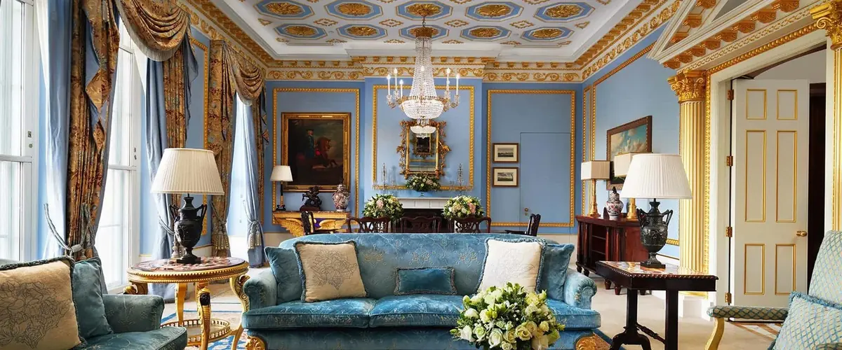 The Lanesborough drawing room with blue panelled walls, ornate ceiling and a blue sofa